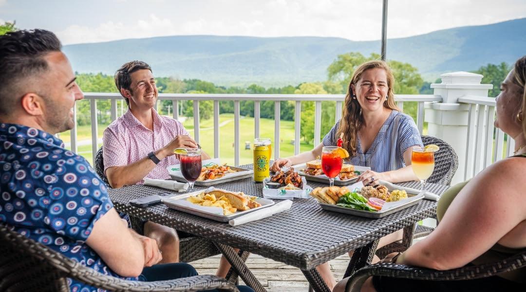 Four people dining on a terrace with mountain views.