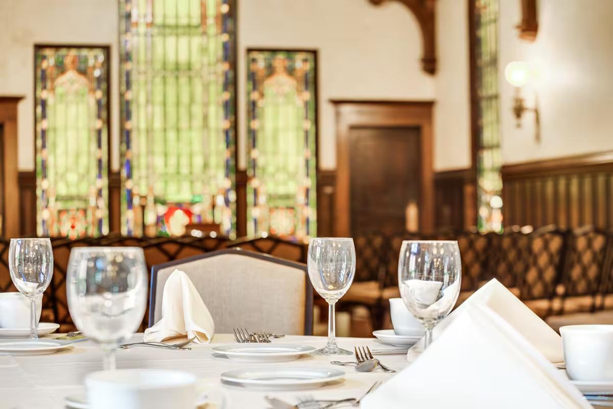 Elegant dining room set with glassware, white napkins, and vintage windows in the background.
