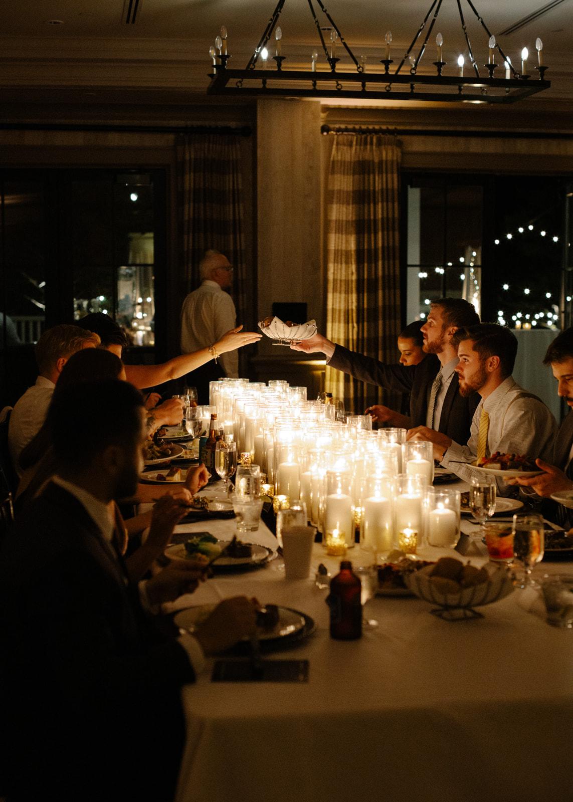 Candlelit dinner with people sitting at a long table.