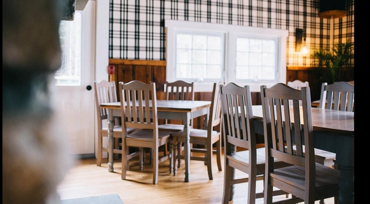 Cozy dining room with wooden tables and chairs by a window.