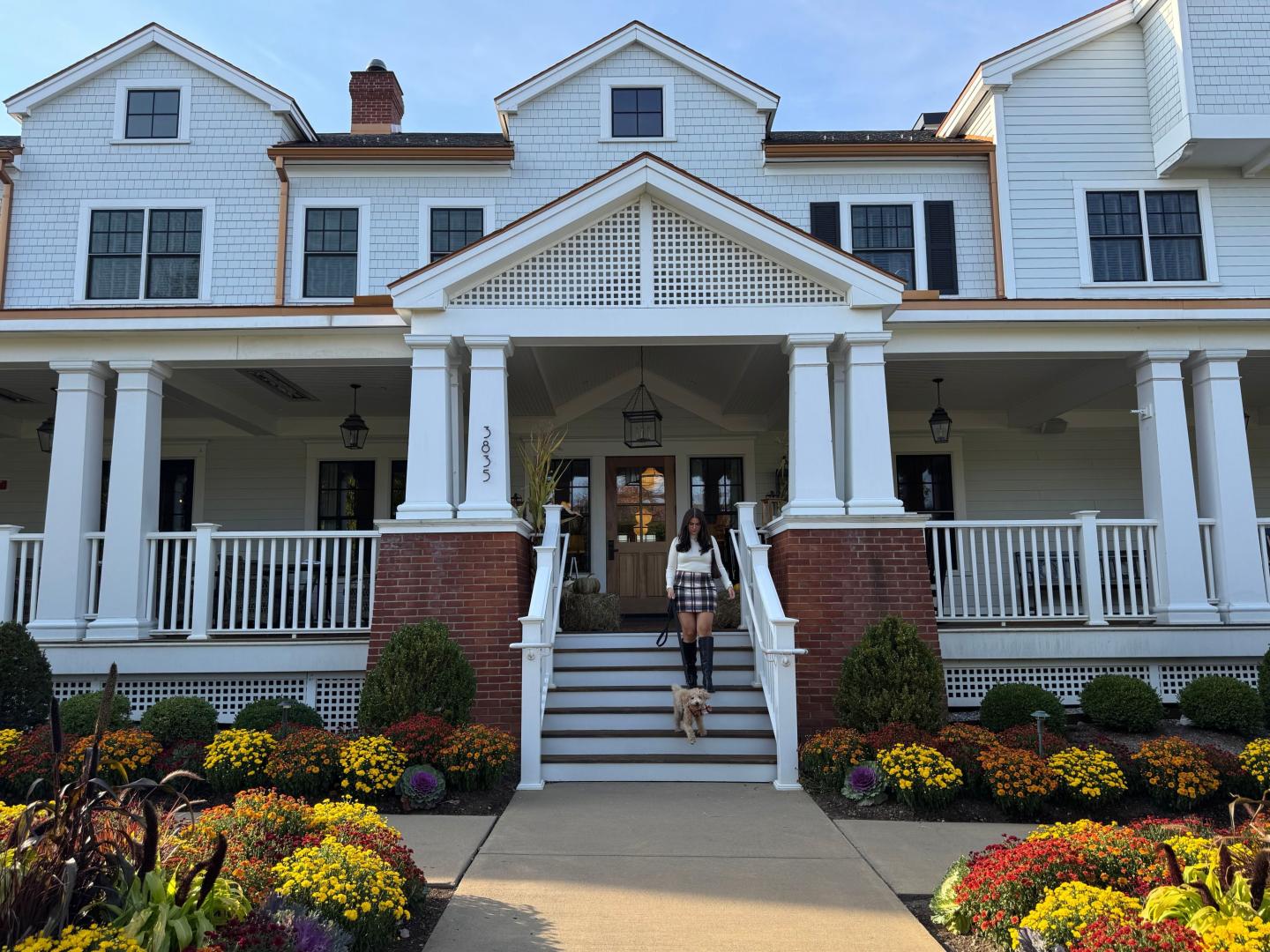 Large white house with columns, colorful flowers in front.
