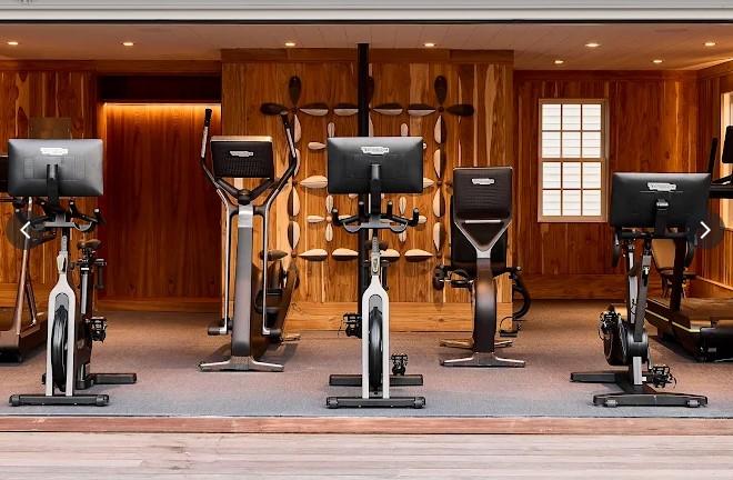 Row of stationary bikes in a wooden gym room.