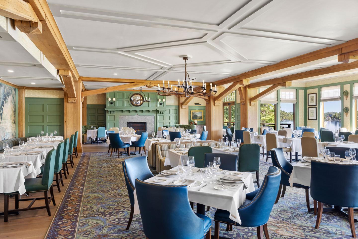 Elegant dining room with white tablecloths, green walls, and blue chairs.