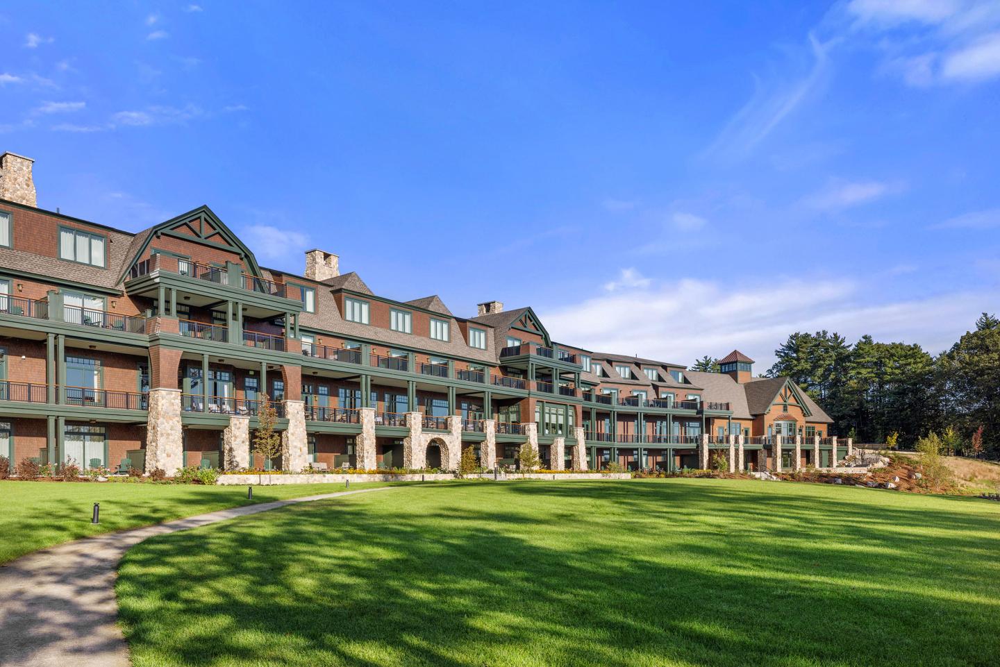 Lodge with balconies and lawn under a clear blue sky.