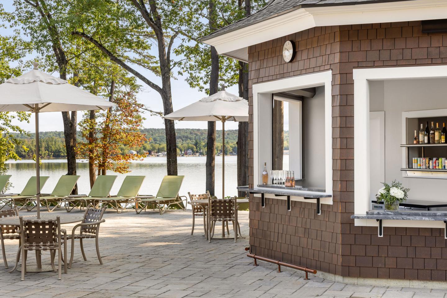 Outdoor patio bar with tables, umbrellas, and lake view.