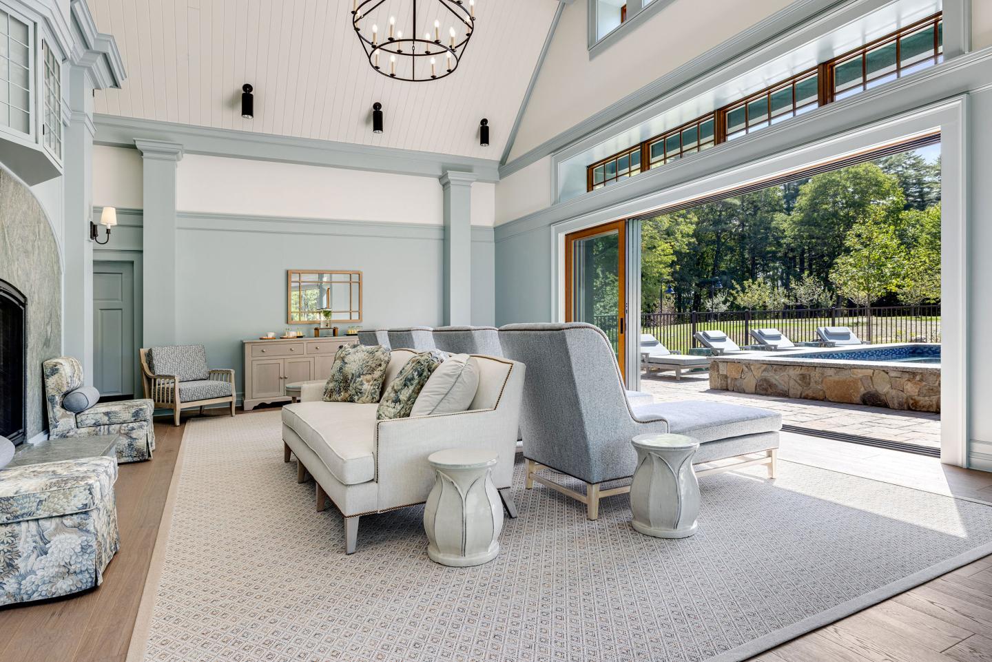Bright living room with large windows, white furniture, and view of a garden.