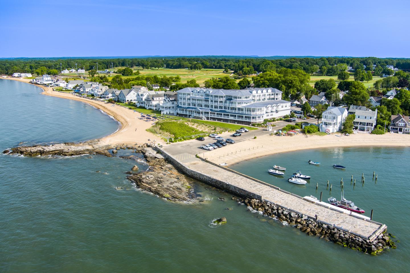 Coastal town with a pier, sandy beaches, and blue ocean under a clear sky.