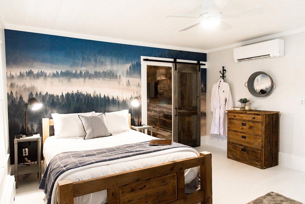 Cozy bedroom with forest mural, wooden bed, dresser, and soft lighting.