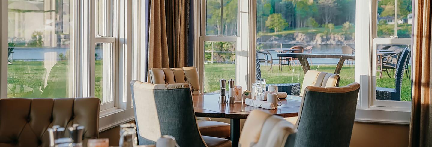 Dining area with lake view through large windows, chairs around a table.