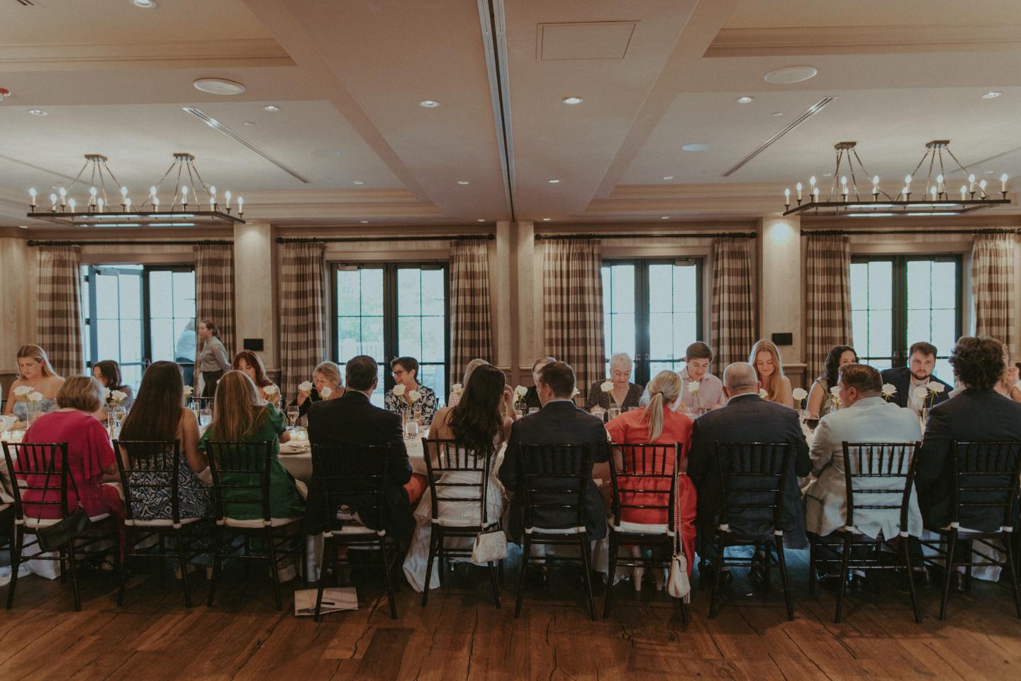 Guests seated around a large banquet table in an elegant dining room.