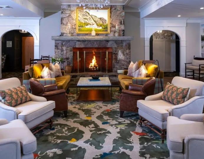 Cozy hotel lounge with armchairs, sofas, and a fireplace.