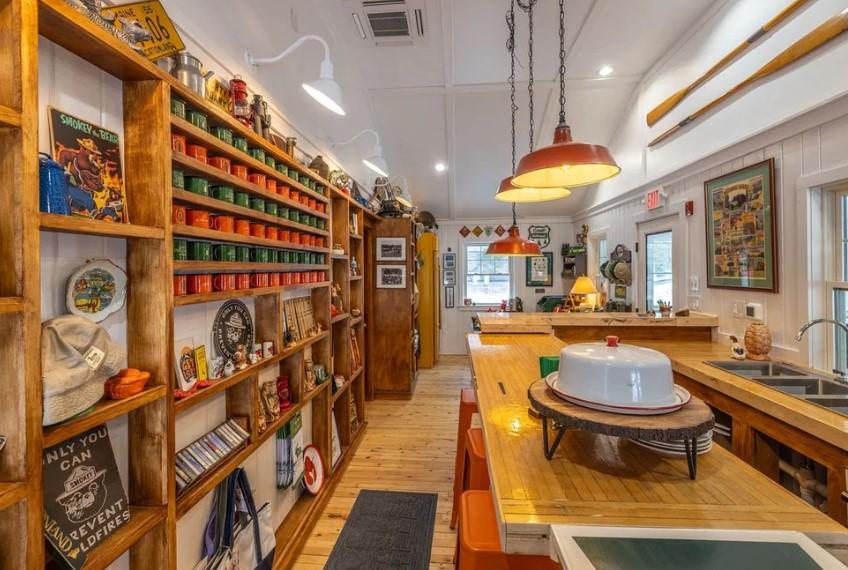 Cozy kitchen with wooden shelves, colorful jars, warm lighting, and a central island.