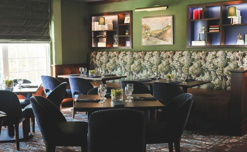 Cozy restaurant interior with floral wallpaper and elegant table settings.