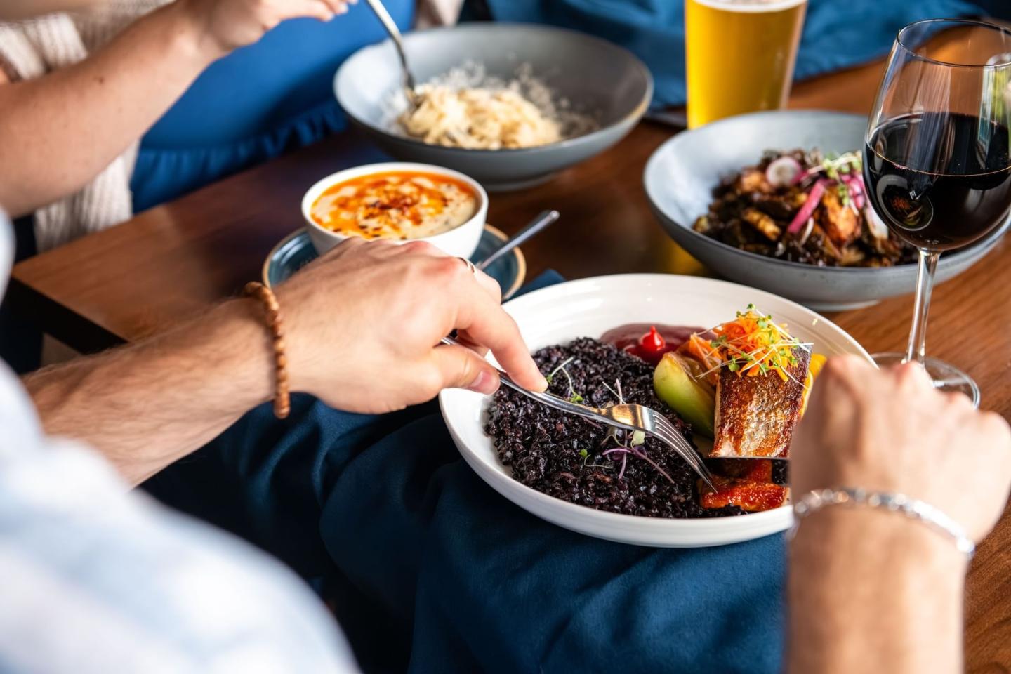 Dining with various dishes, including fish, rice, beans, and drinks on a table.