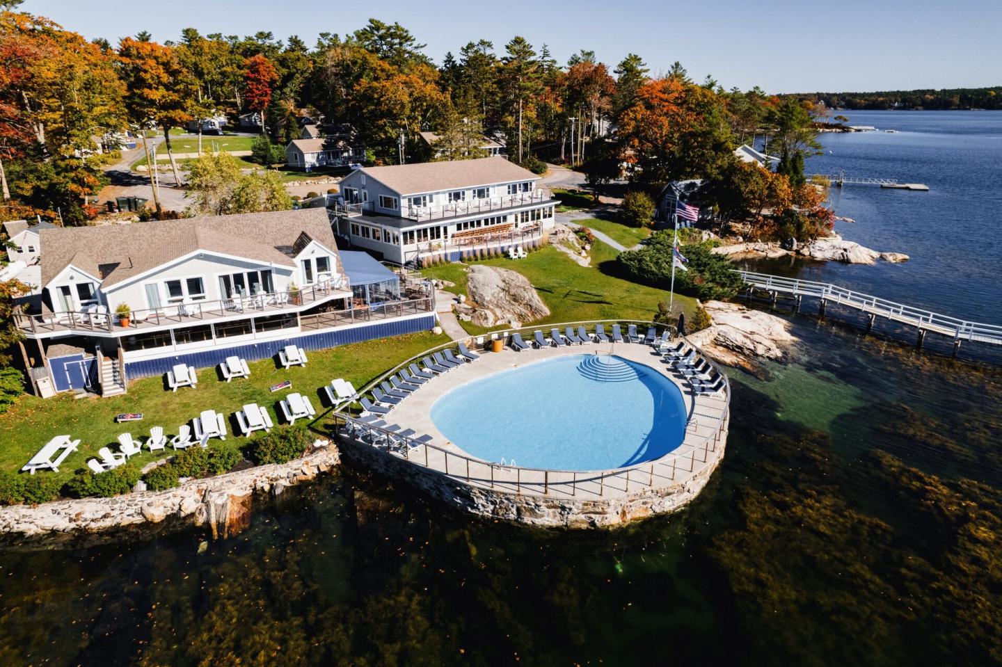 Coastal resort with infinity pool, surrounded by autumn trees and ocean.