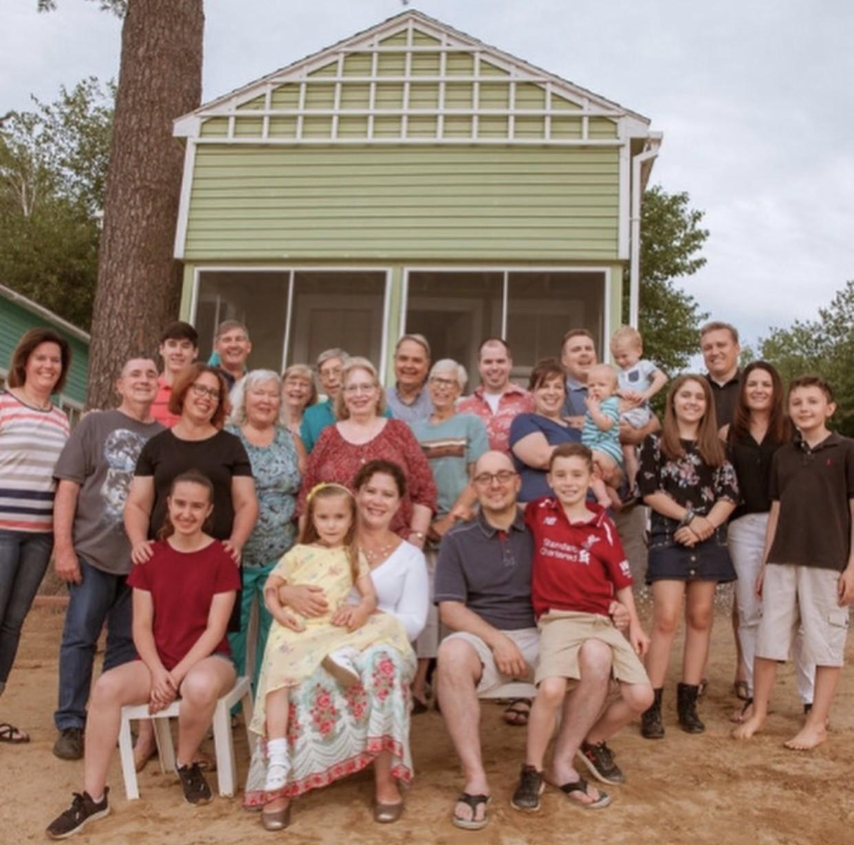 Family group posing in front of a light green house.