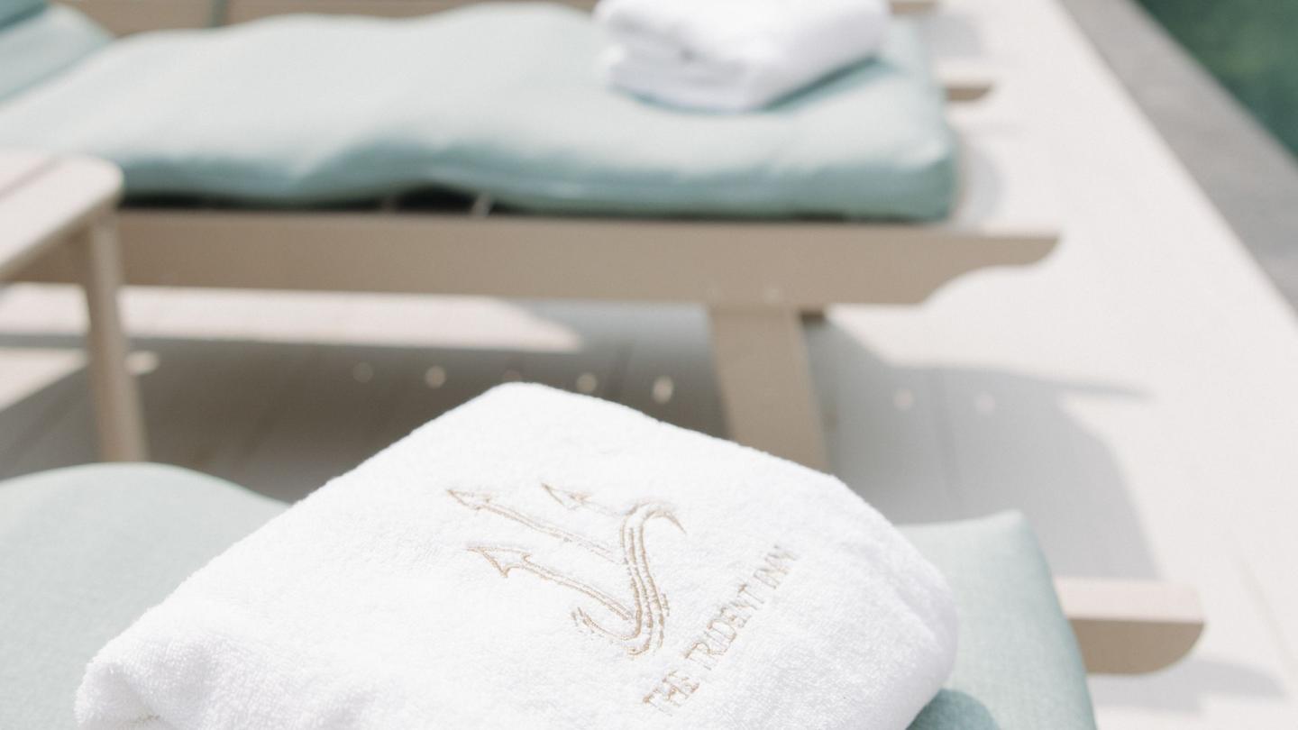 White towels on light green lounge chairs, poolside setting.