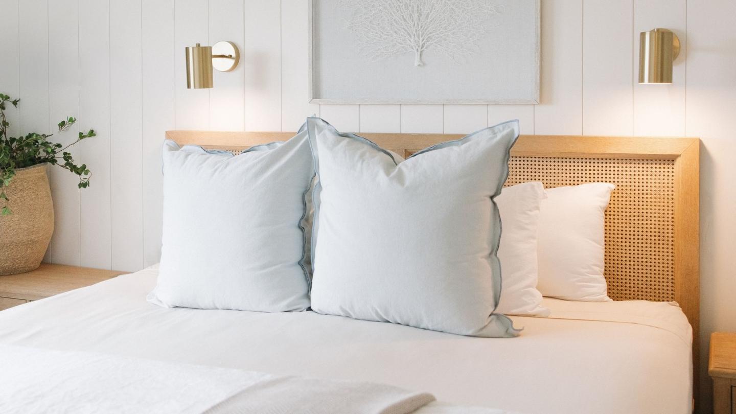 Bedroom with white pillows on a wooden bed, soft lighting.