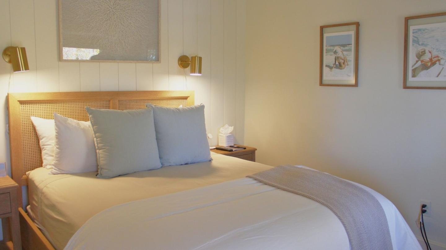 Cozy bedroom with a neatly made bed, wooden headboard, and wall art.
