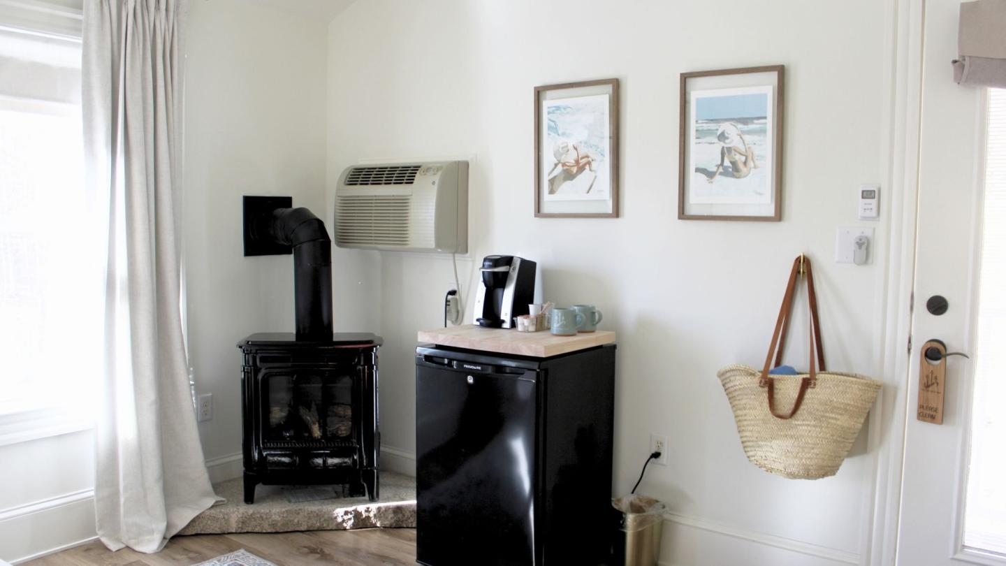Cozy room with a black stove, small fridge, and beach-themed decor.