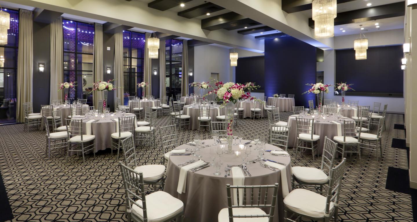 Ballroom event space with tables and chairs, full length windows 