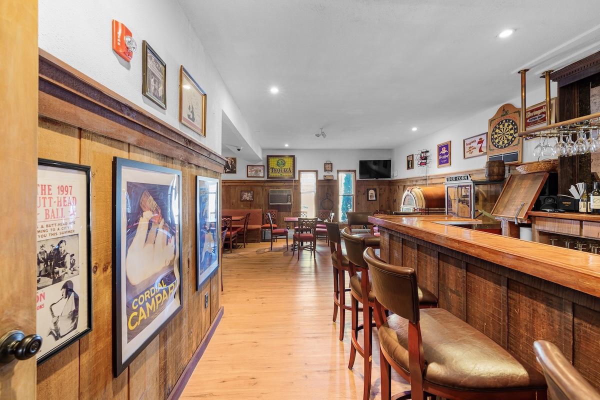 Cozy bar interior with wooden decor, stools, and vintage posters on the walls.