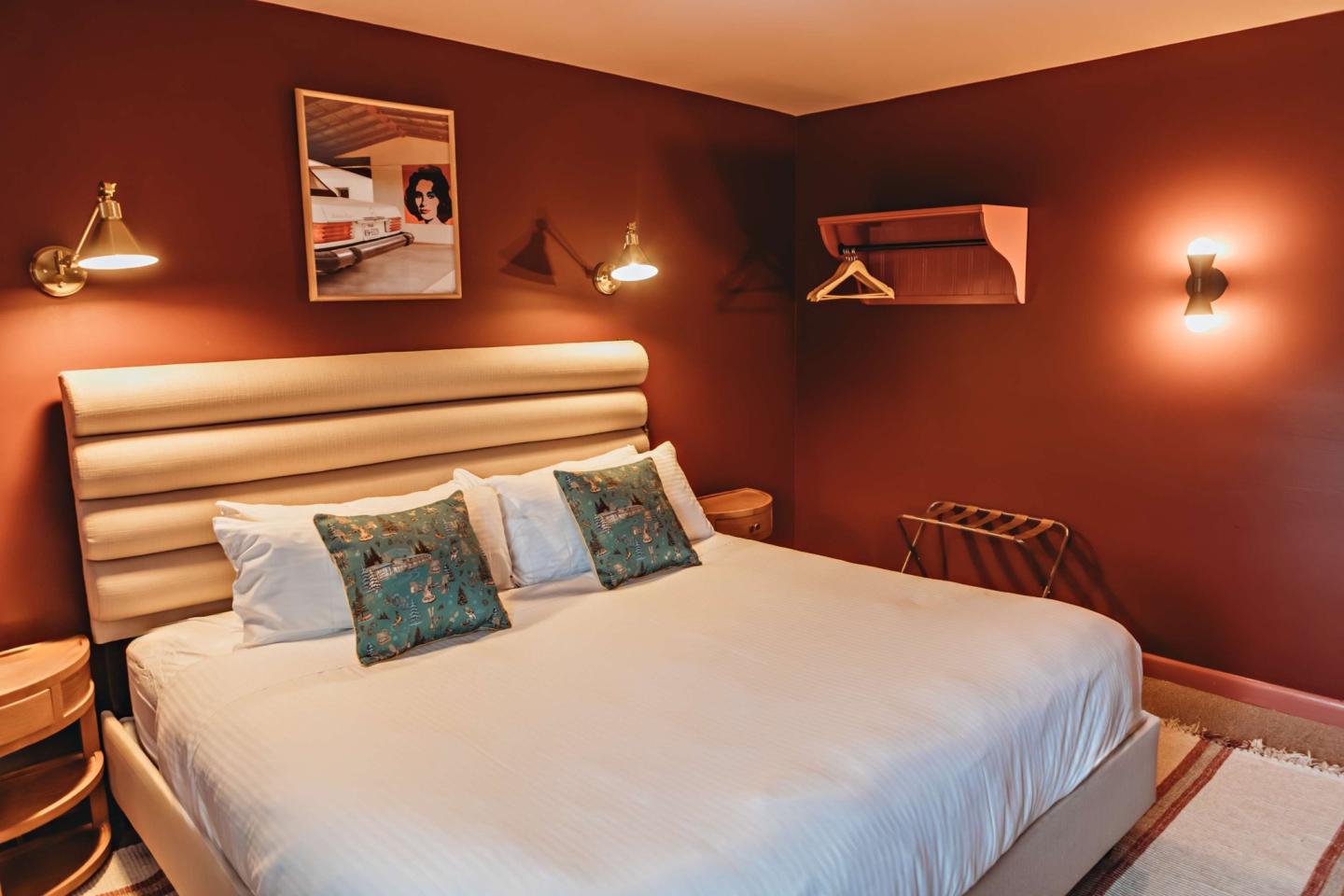Cozy bedroom with a double bed, wall lamps, and a maroon accent wall.