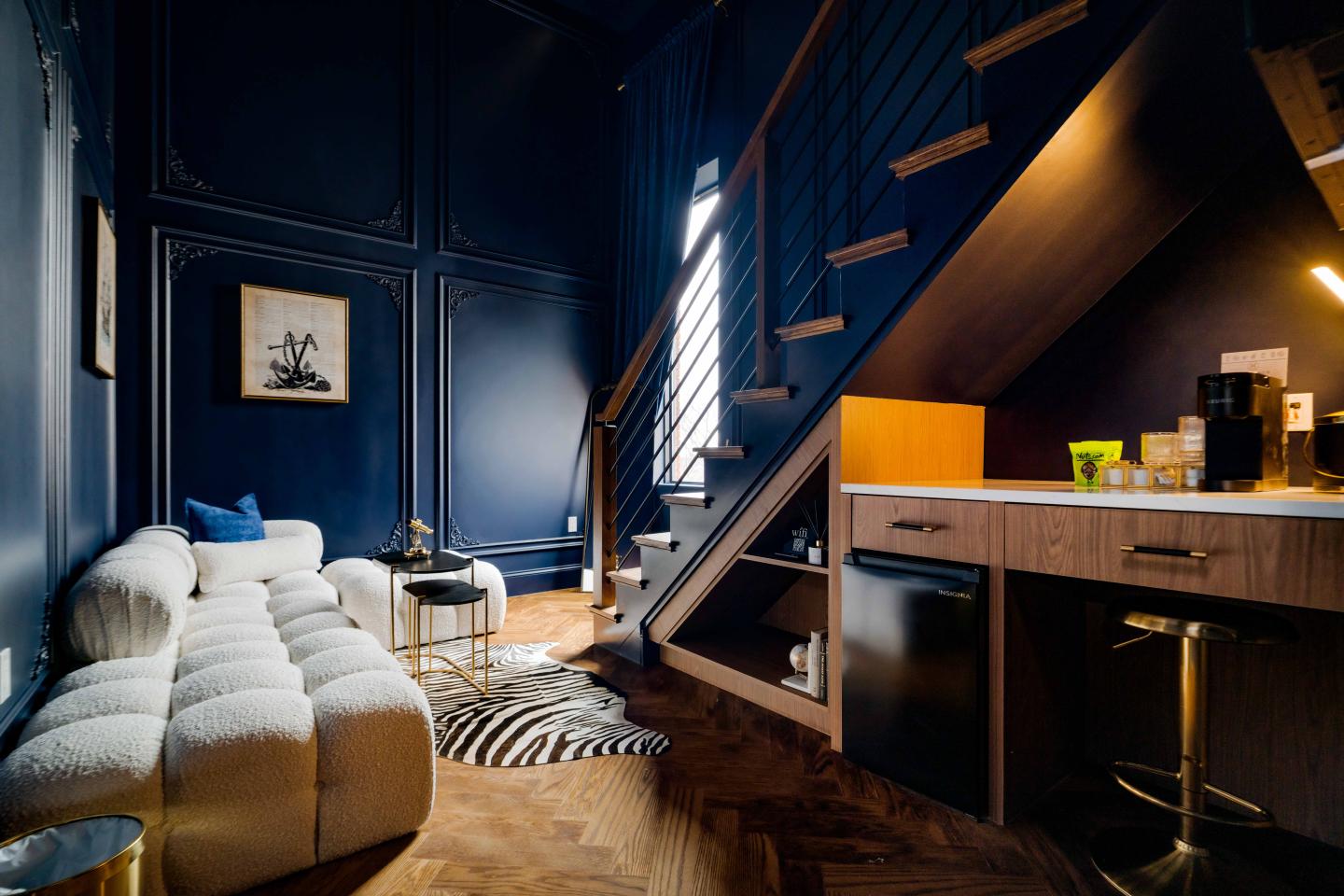 Cozy living space with a white couch, under-stair kitchen, and navy walls.