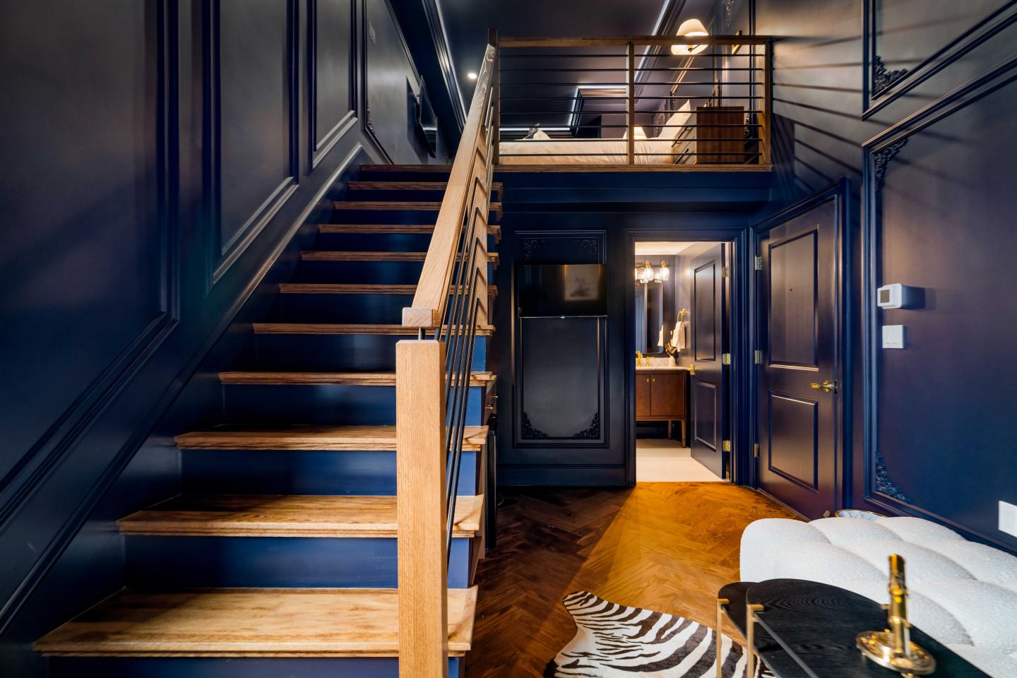 Luxurious interior with navy walls, wooden staircase, and elegant furnishings.