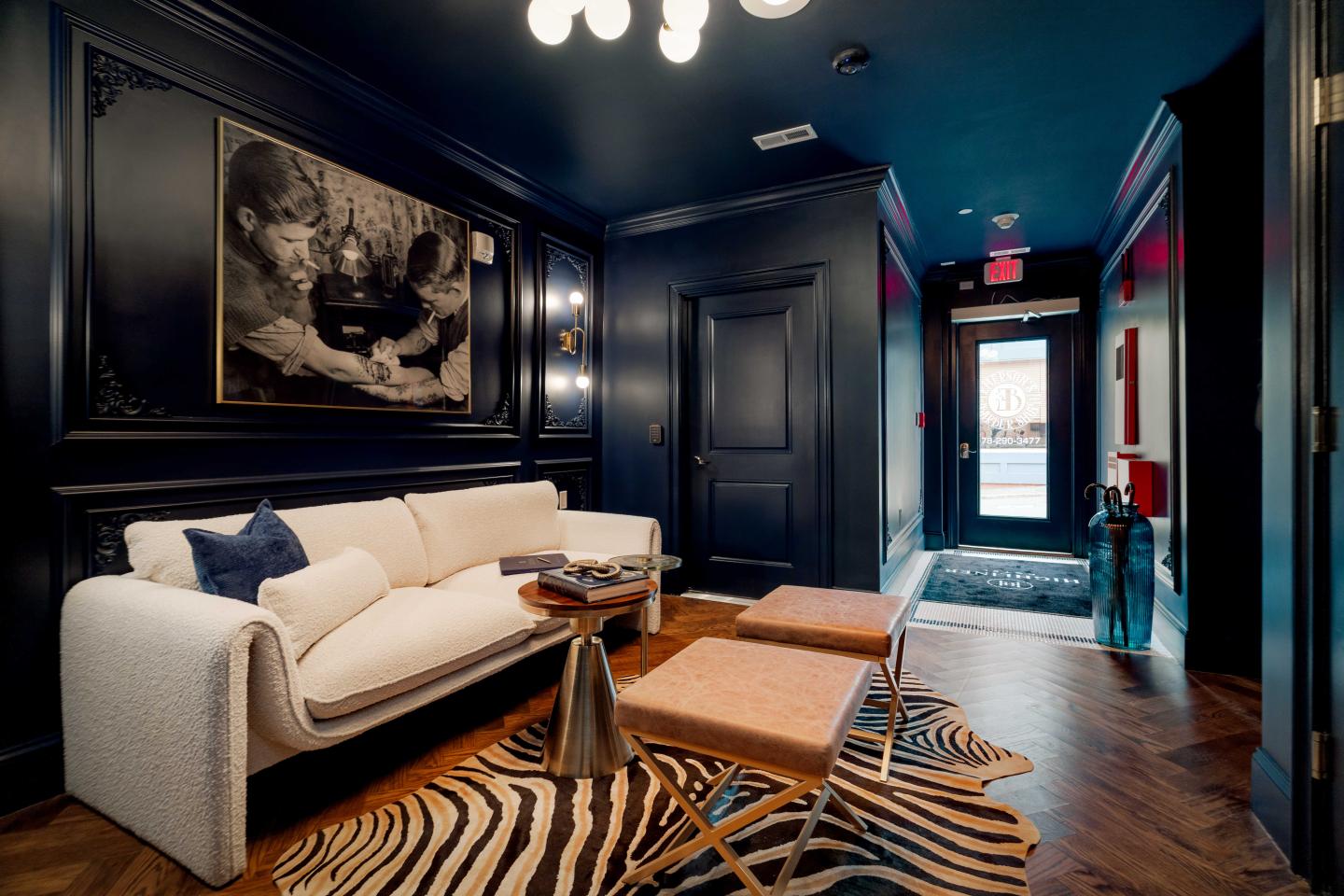 Sophisticated lounge with white sofa, zebra rug, and wall art in dim lighting.