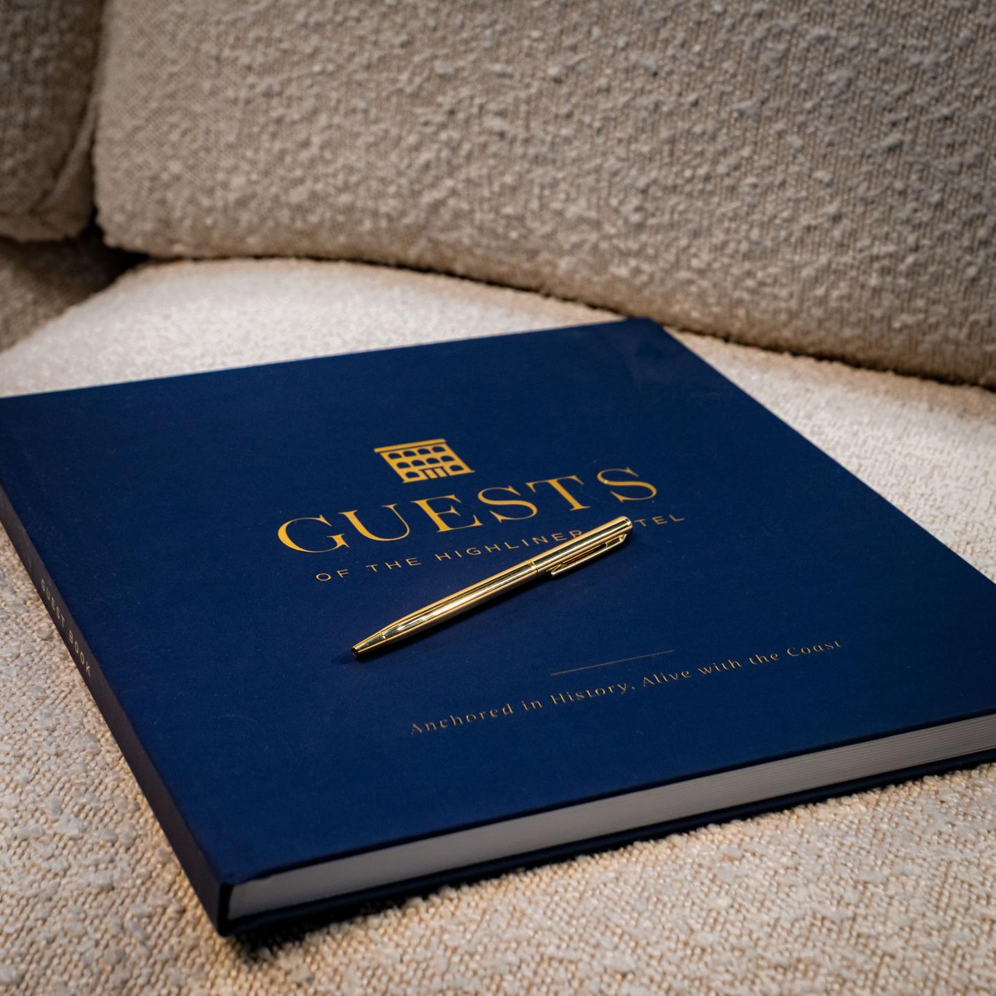 Guest book with pen on beige couch.