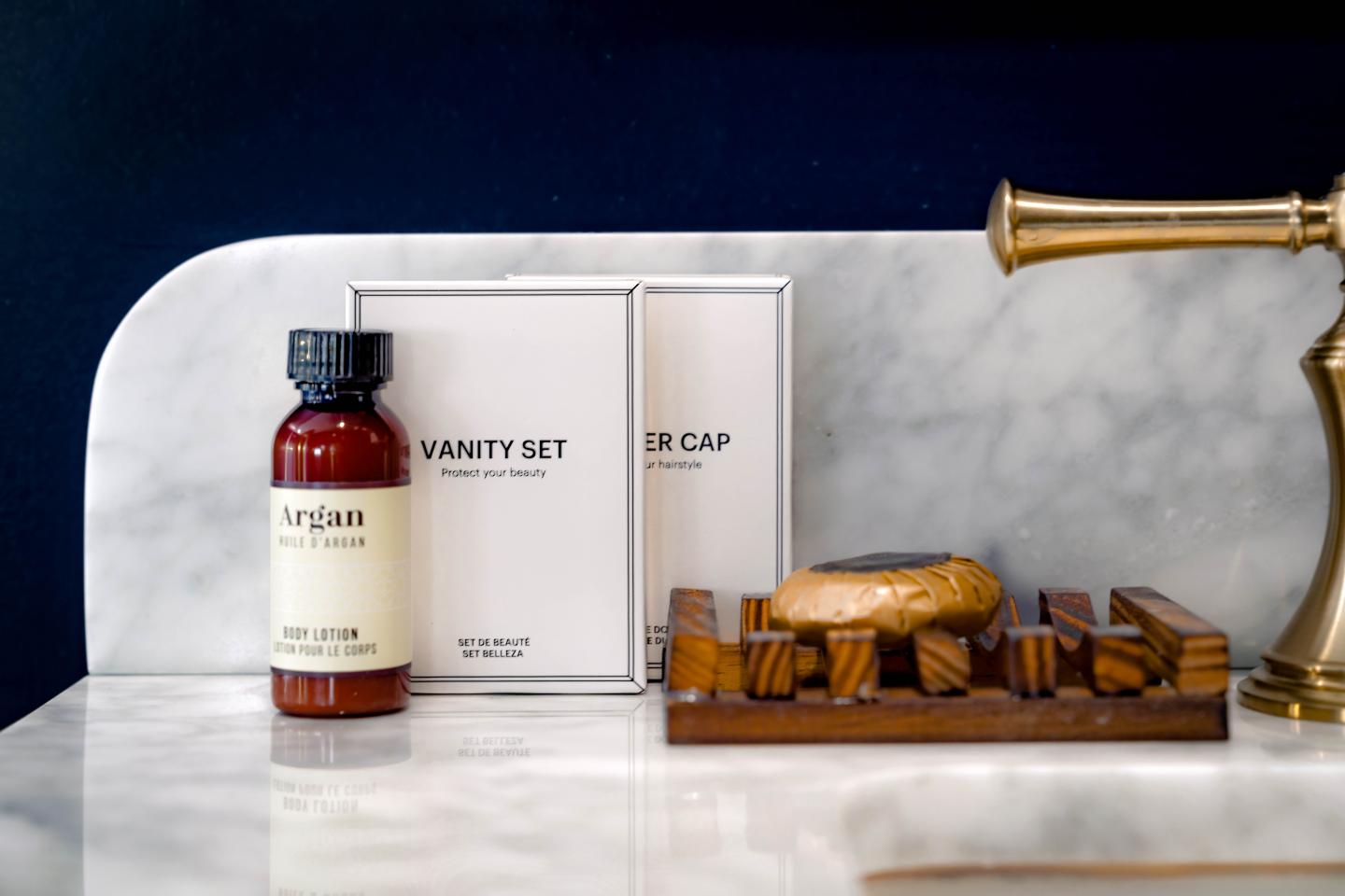 Toiletries on marble counter with brass faucet.