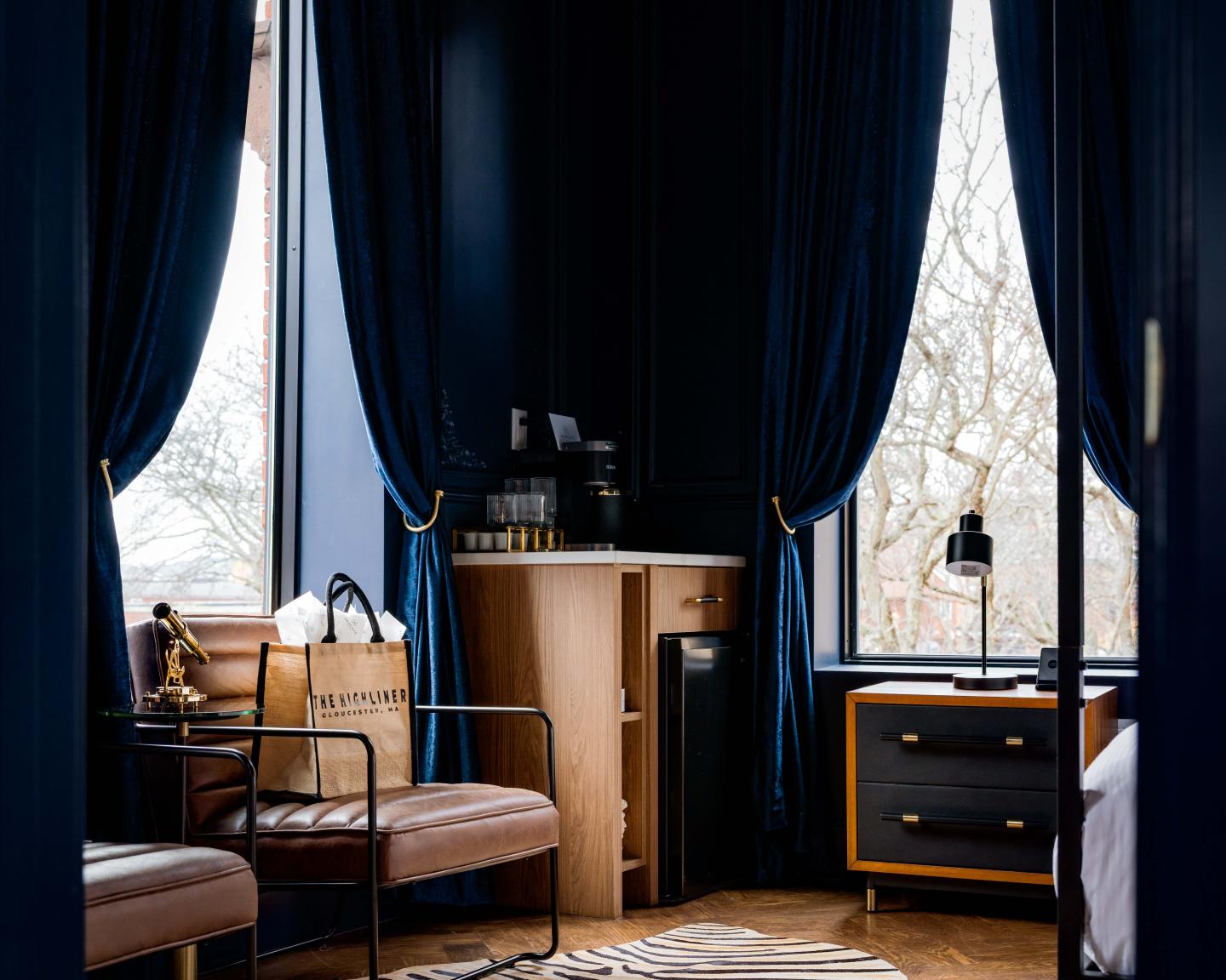 Cozy room with blue curtains, leather chairs, and a wooden dresser.