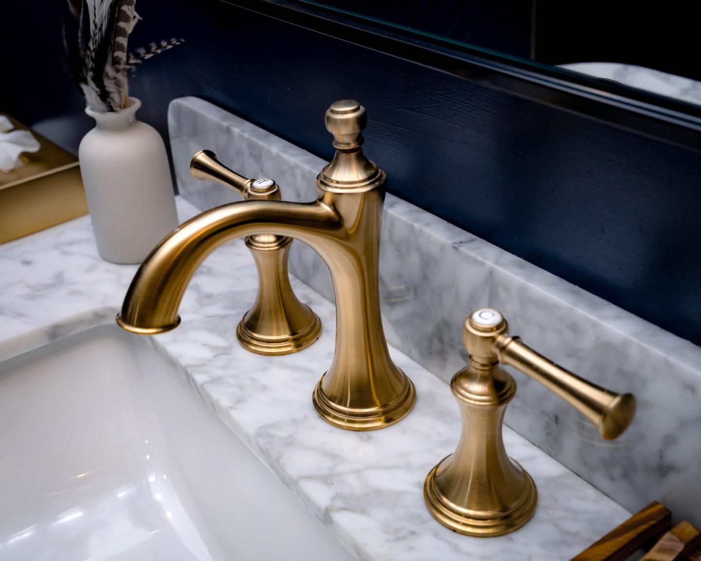 Gold bathroom faucet set on marble counter.