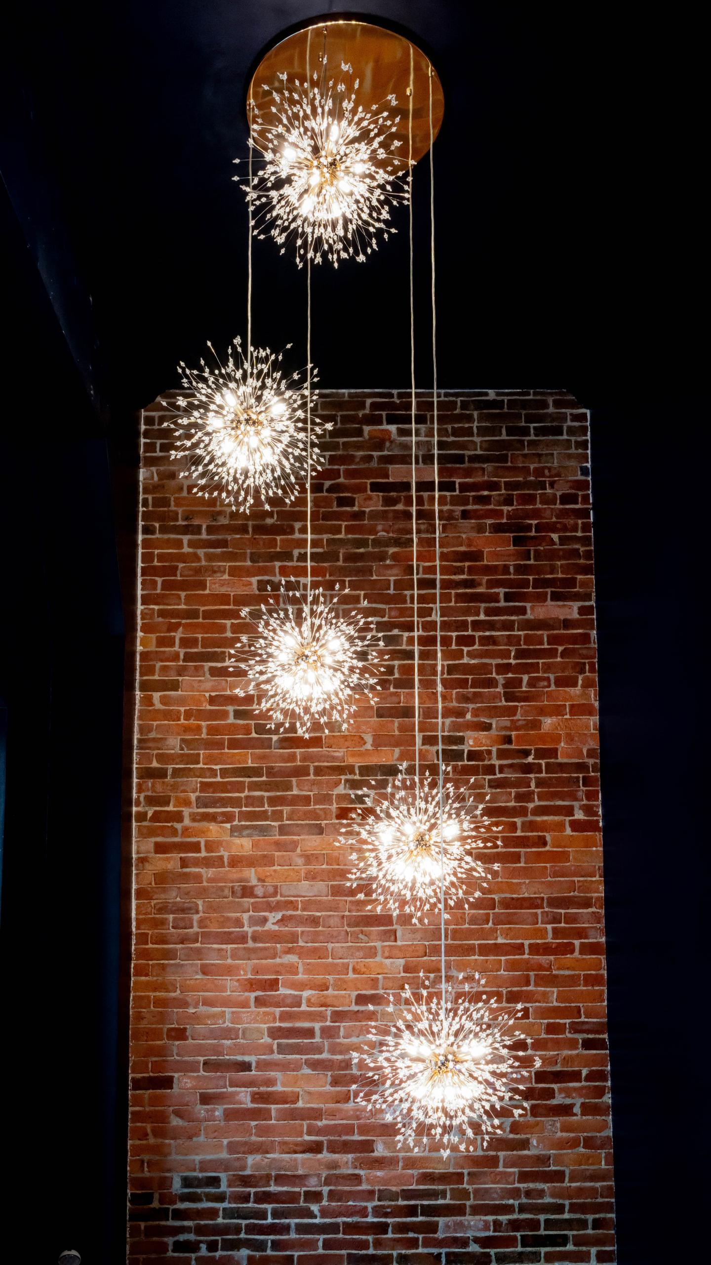 Five spherical pendant lights hang against a brick wall.