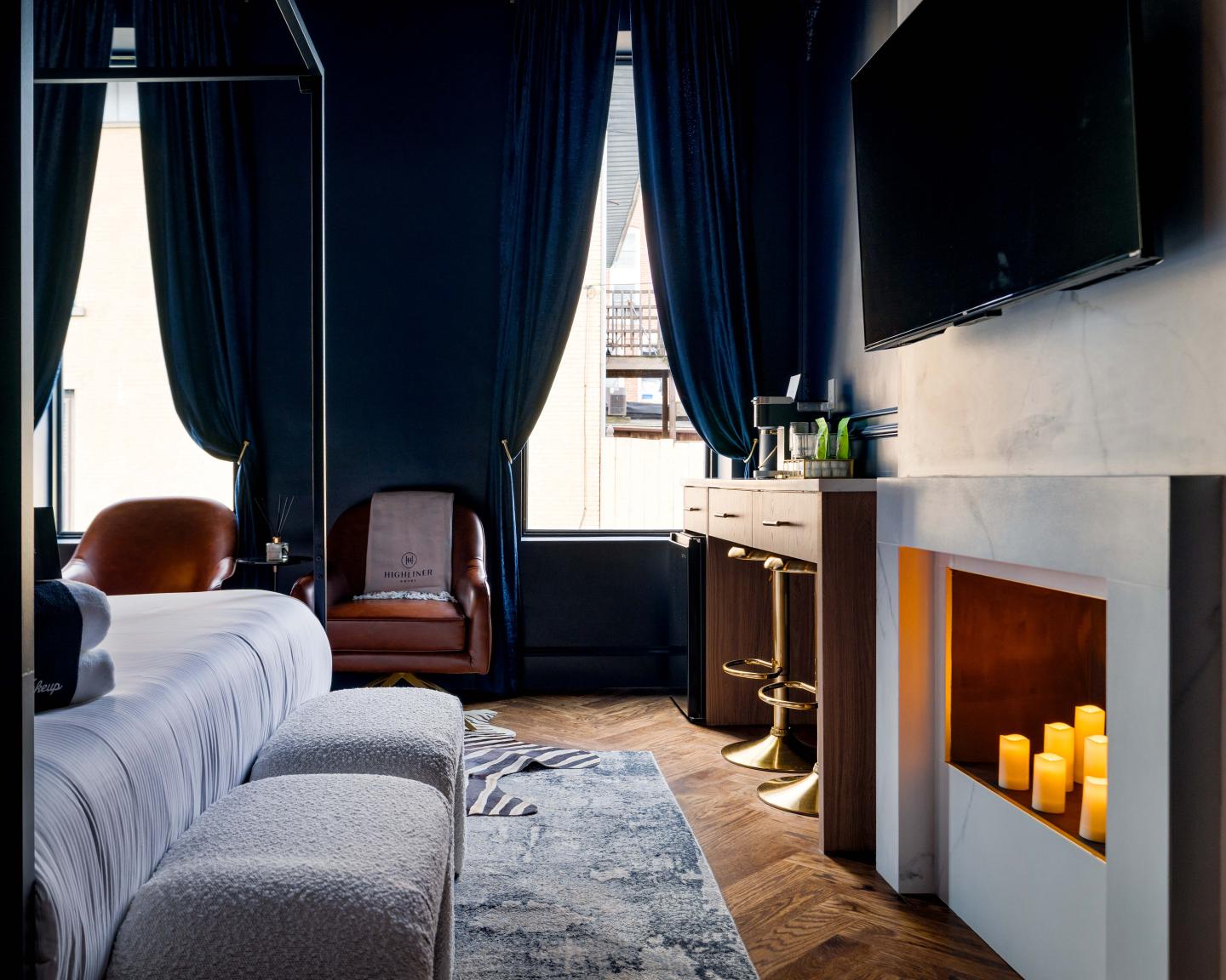 Cozy bedroom with dark curtains, modern fireplace, and large bed.