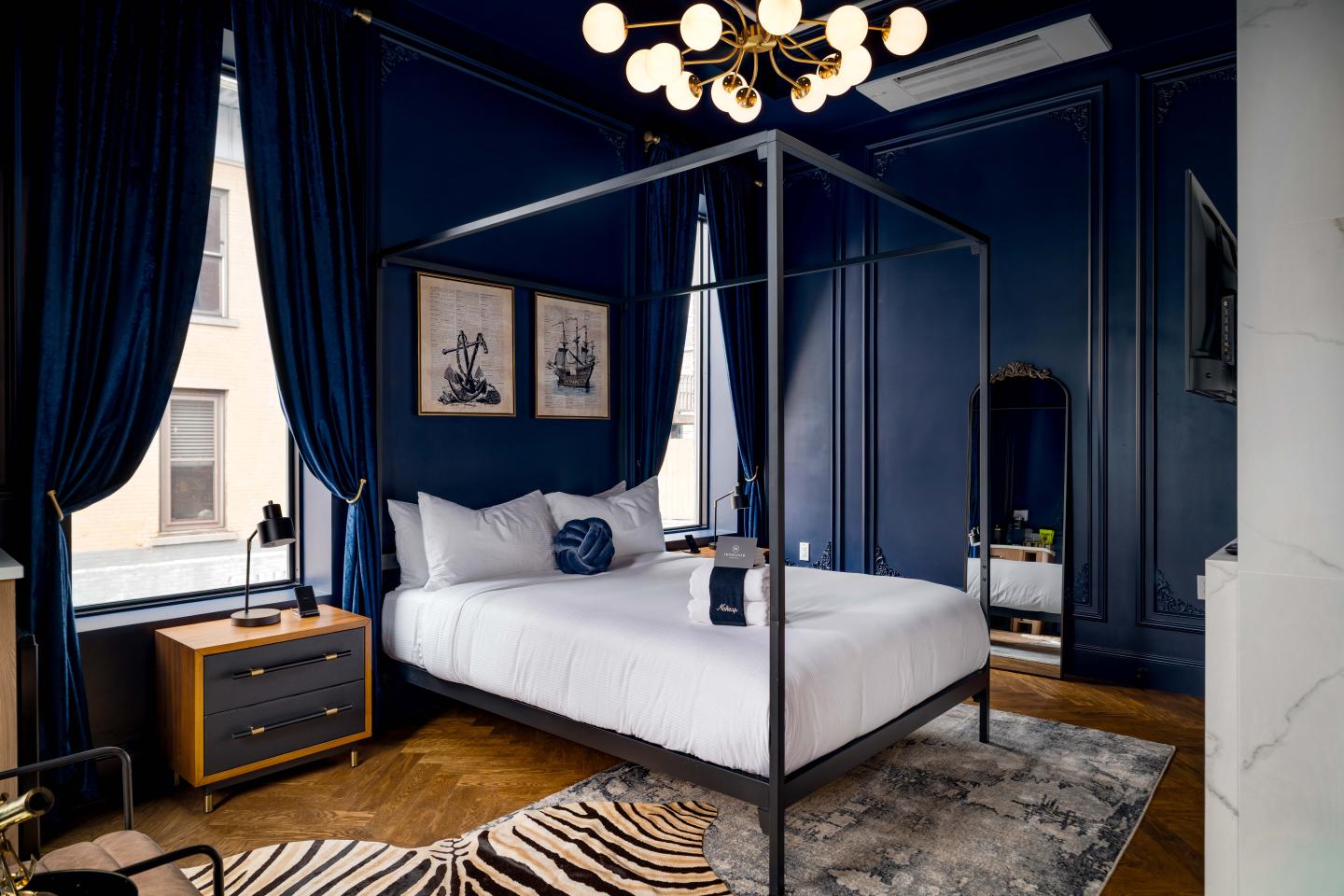 Elegant bedroom with blue walls, a canopy bed, and modern chandelier.