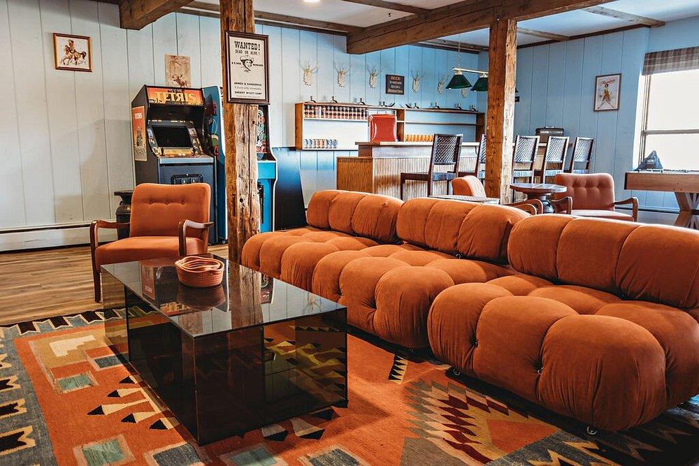 Retro living room with a brown sofa, patterned rug, and arcade machine.