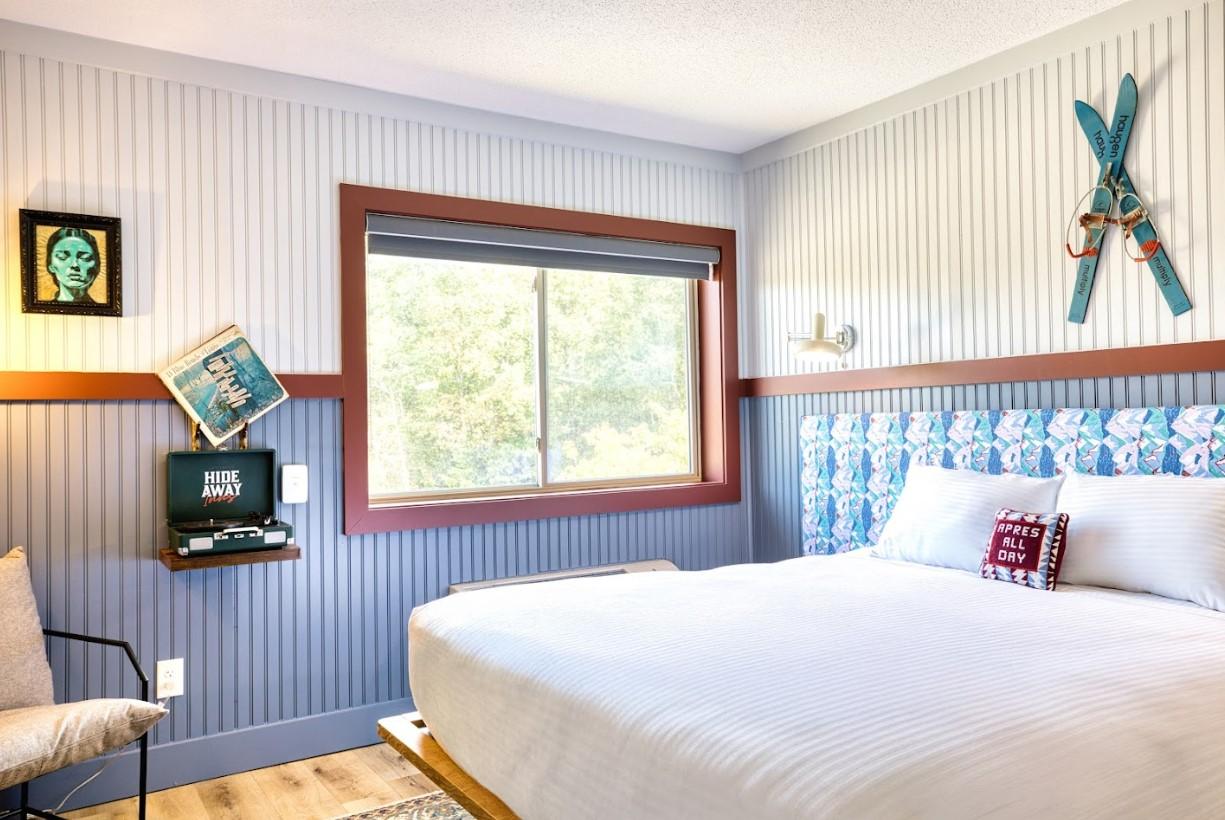 Cozy bedroom with a large bed, window, and skis mounted on the wall.