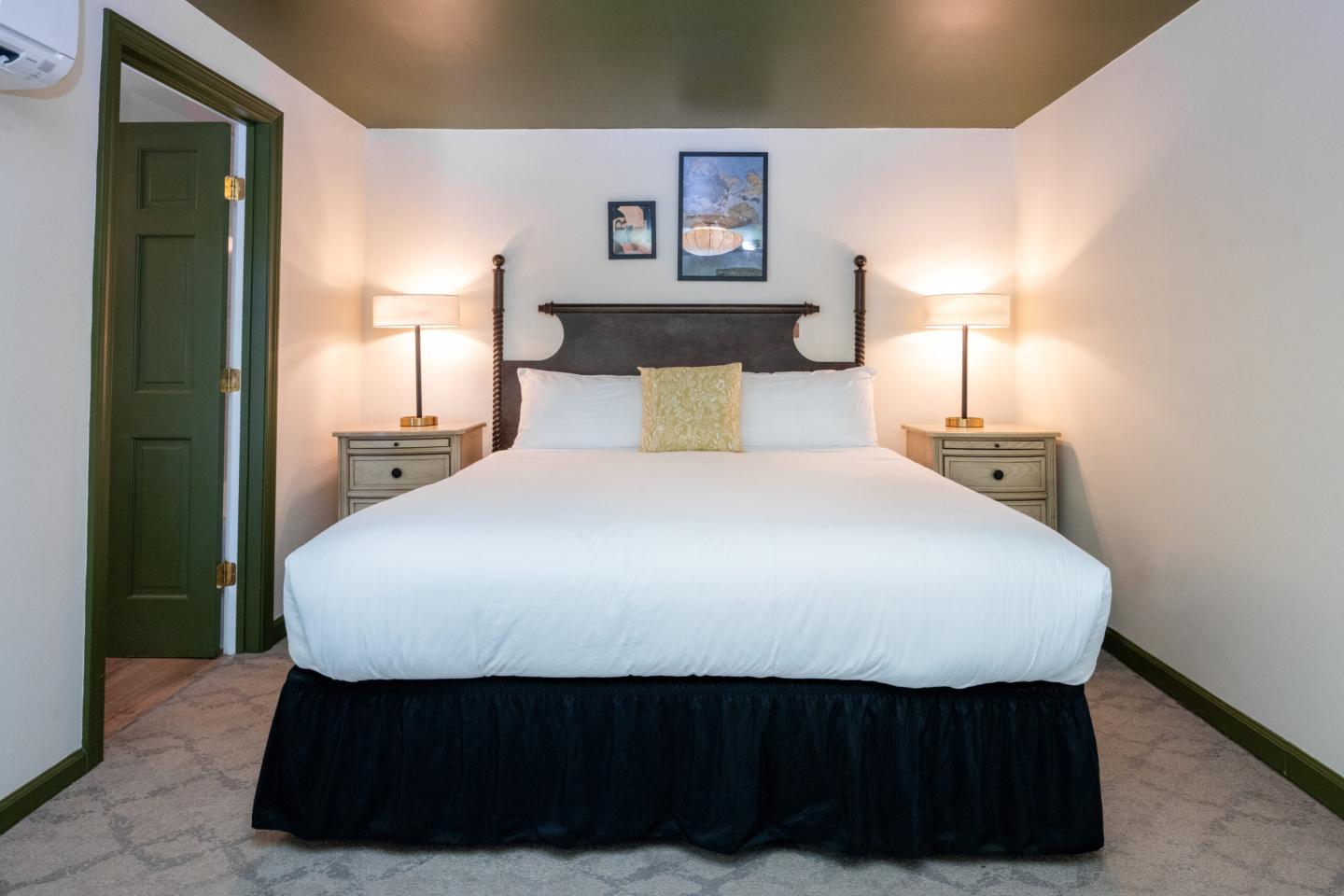 Cozy bedroom with a large bed, two lamps on side tables, and wall artwork.