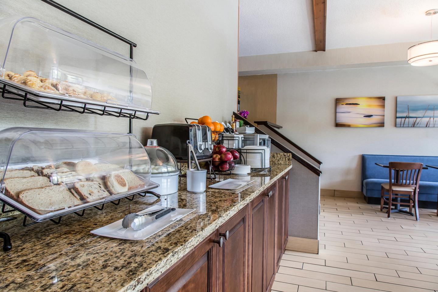 Breakfast area with pastries, fruit, and juice on a counter in a dining room setting.