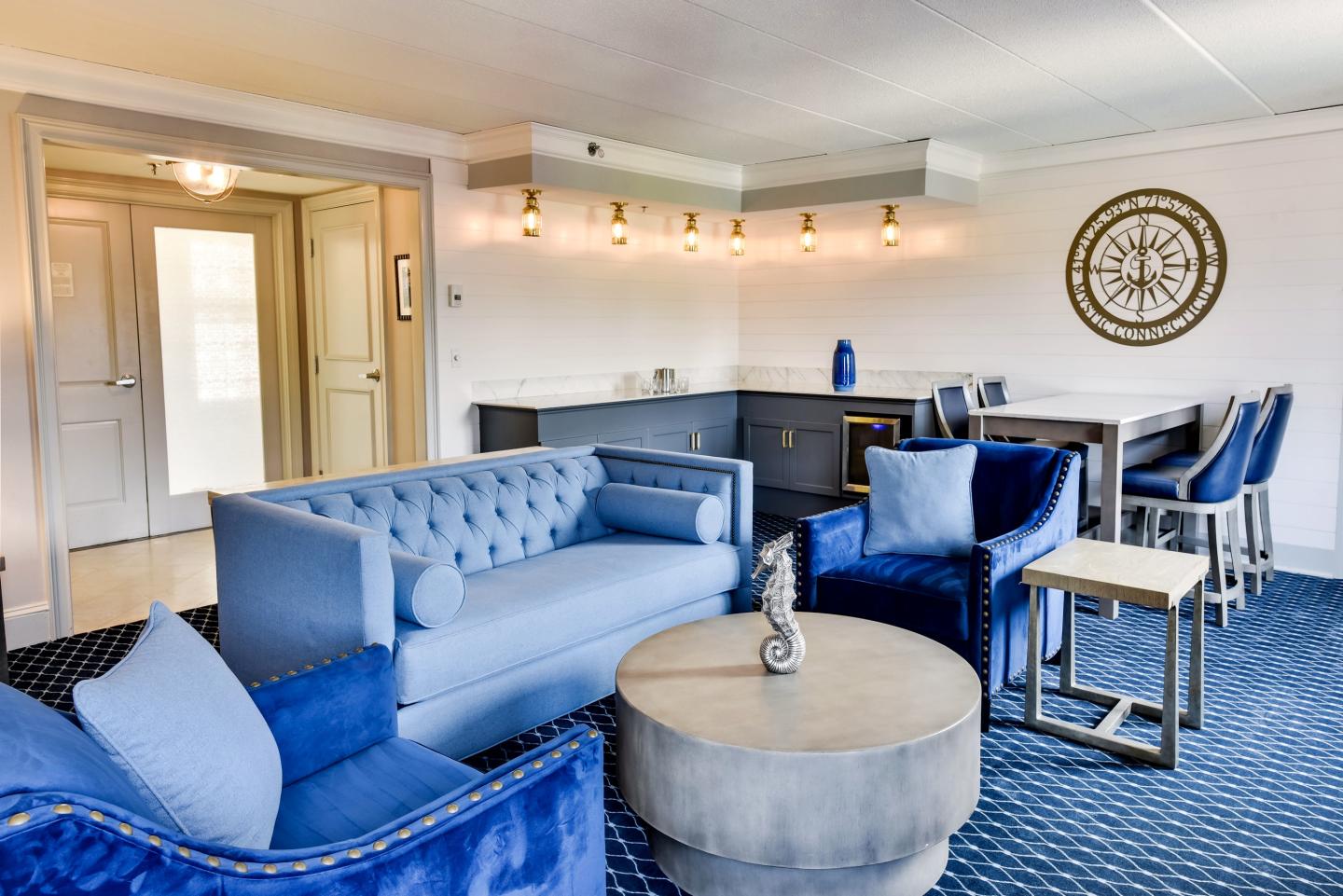 Luxurious living room with blue couches, round table, and modern decor.