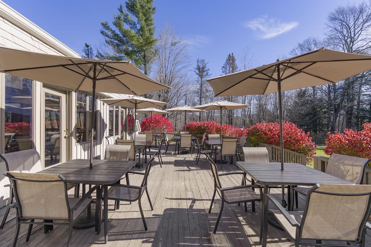 Outdoor patio with tables, chairs, and umbrellas under a clear blue sky.