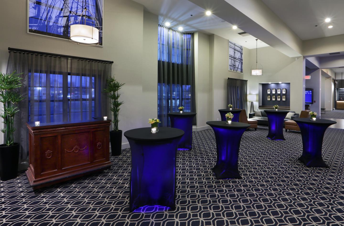 Reception area with tall tables, blue lighting, and elegant decor.