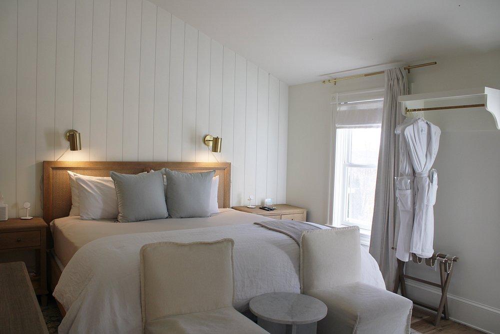 Cozy bedroom with a large bed, soft lighting, and a robe hanging near the window.