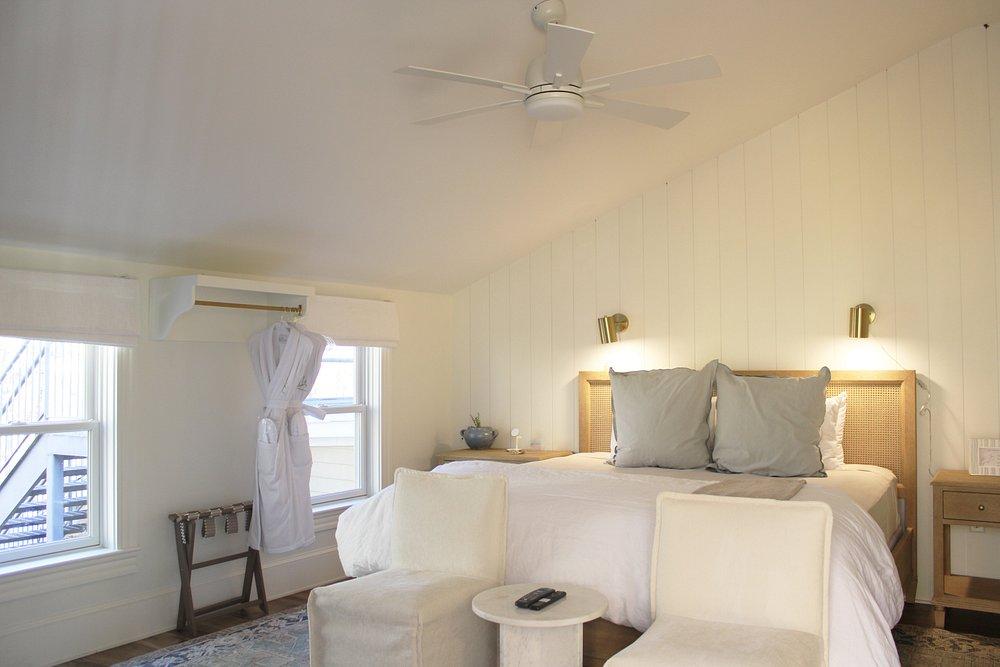 Cozy bedroom with a large bed, gray pillows, and beige chairs.