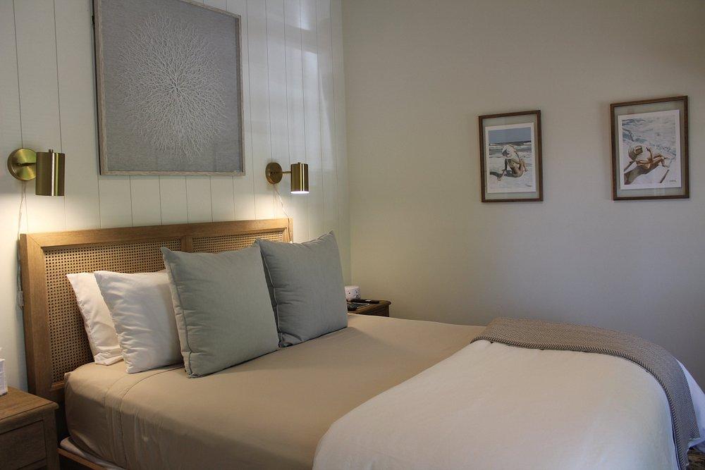 Cozy bedroom with a neatly made bed, two pillows, and framed art on the walls.