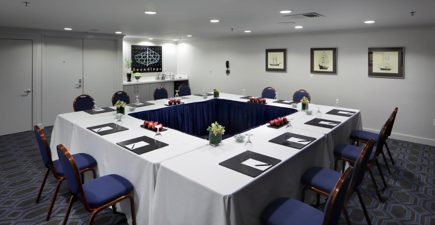 Conference room with a U-shaped table, navy chairs, and framed art on the walls.