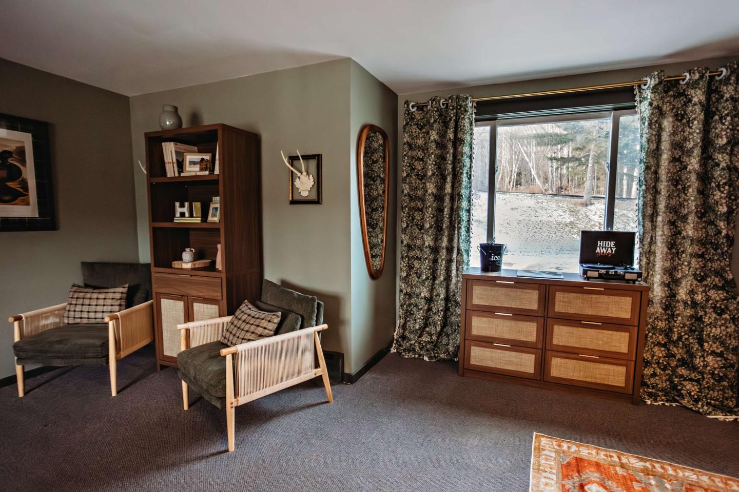 Cozy living room with armchairs, bookshelf, and a large window.