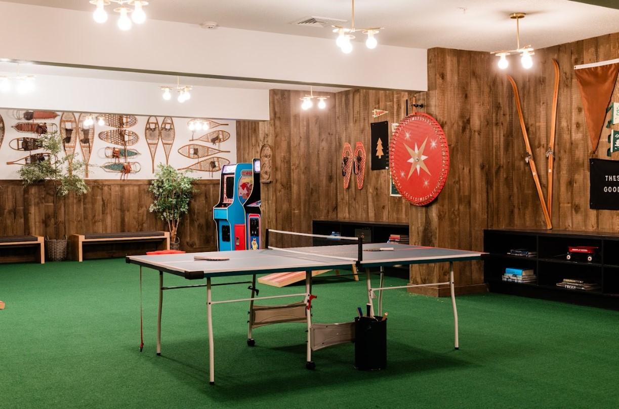 Ping pong table in a carpeted room with wooden walls and sports decor.